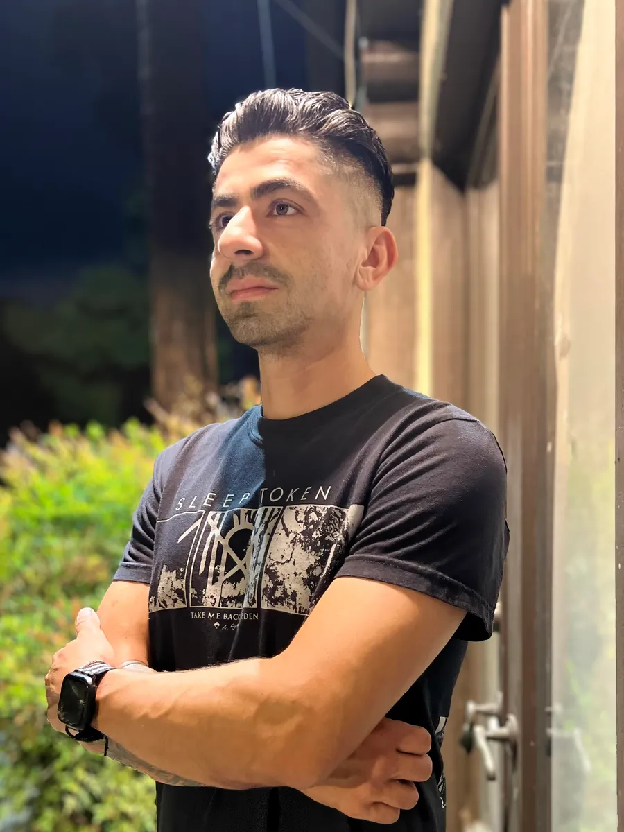 Jaime standing outside in the evening, arms crossed